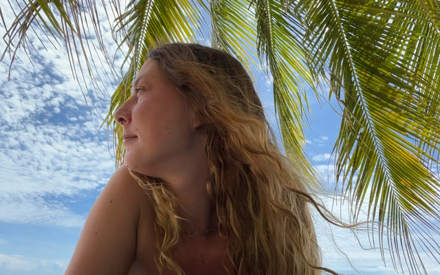 Sarah unter einer Palme mit Blick aufs Meer